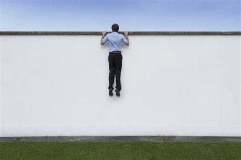 Business man looking over wall stock photo