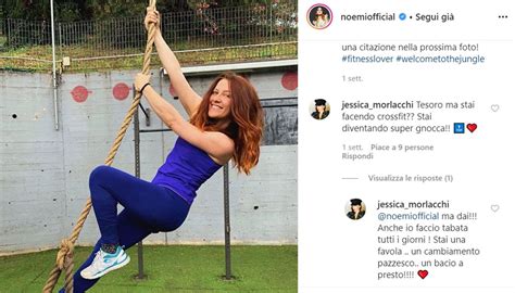 a woman in blue shirt and leggings on a rope with one hand up