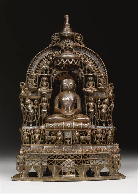 an old bronze buddha statue sitting on top of a wooden stand with carvings around it