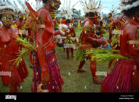 Colourfully dressed and face painted women dancing as part of a Sing Sing in Madang, Papua New ...