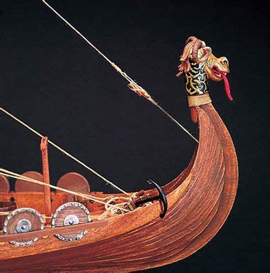 an elaborate wooden model of a boat with two sails and a woman on the front