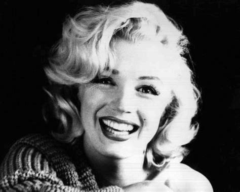 a black and white photo of a woman with blonde hair smiling at the camera,