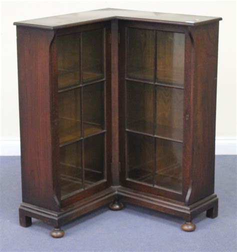 A George V oak 'L' shaped corner bookcase, fitted with a pair of glazed ...