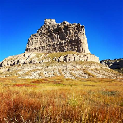 a large rock formation towering over a dry grass field