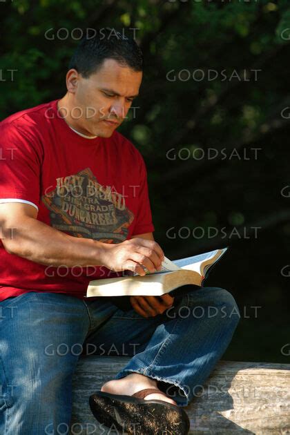 Man reading book outdoors in summer. - GoodSalt