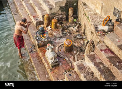 man offers water to the Ganges as part of a morning prayer ritual at ...