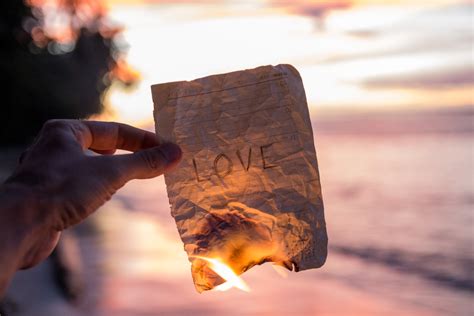 Hand holding a burning paper with word Love - Savvy Tokyo