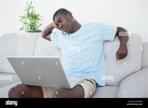 Casual man sitting on sofa using laptop Stock Photo - Alamy