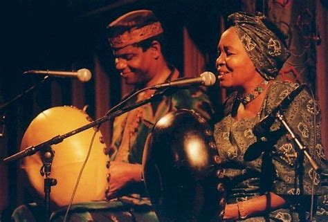 a man and woman playing musical instruments in front of microphones