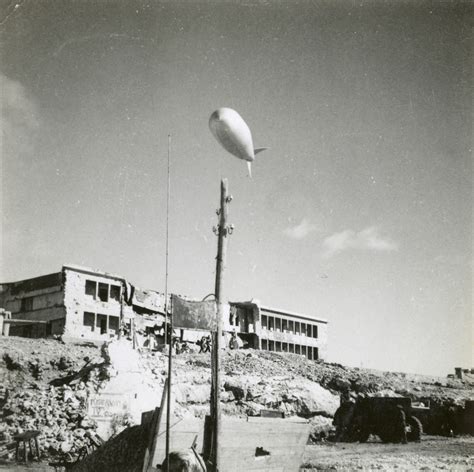 A barrage balloon floats low over a bombed out building near the Suez ...