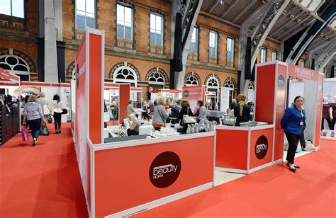 a group of people standing in front of booths at an event with red carpet and white walls