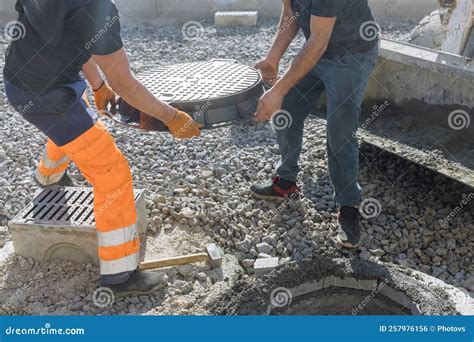 Cast Iron Sewer Hatch Being Installed on a Concrete Base As Part of the Installation of a Water ...