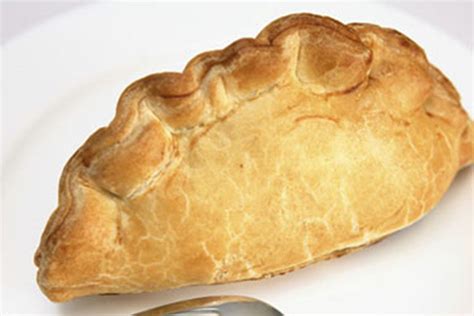 a piece of bread sitting on top of a white plate next to a silver spoon