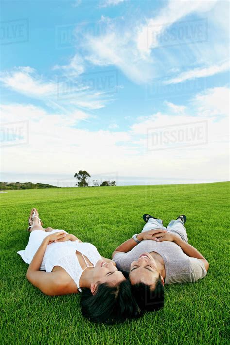 Couple laying in grass in rural landscape - Stock Photo - Dissolve