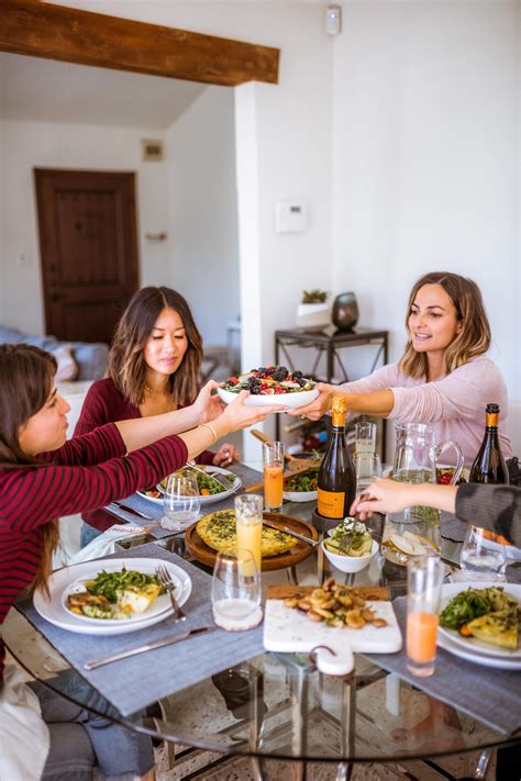 three women sitting at a table with plates of food and drinks in front ...