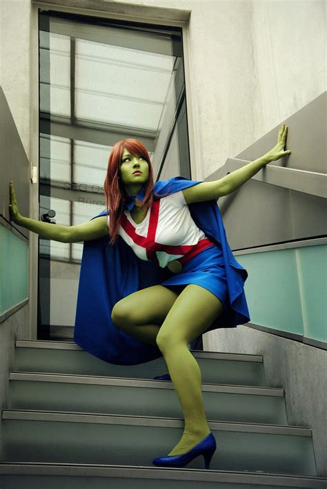 a woman with red hair and green skin is posing on some stairs wearing a blue skirt