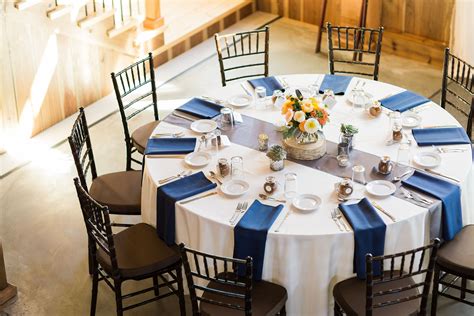 Guest tables: ivory linens, navy napkins, silver shantung table runners (Abbott Rentals), birch ...