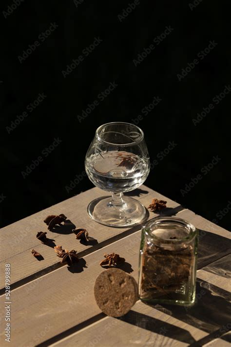 crystal glass with aniseed liqueur, rum, tequila with aniseed seeds, jar with cork lid, wooden ...