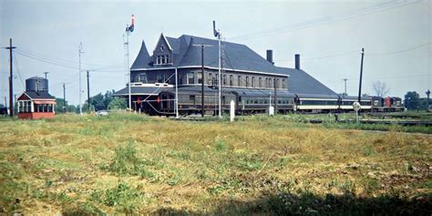 an old train station sits in the middle of a grassy field with power ...