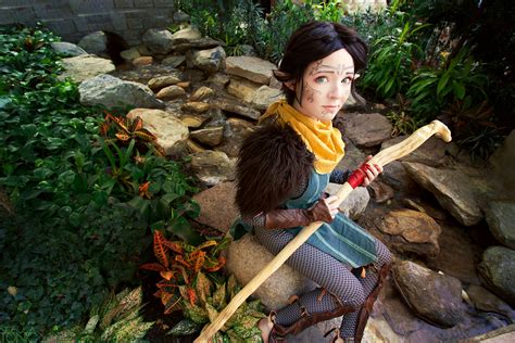 a woman dressed in medieval clothing holding a wooden stick and looking ...