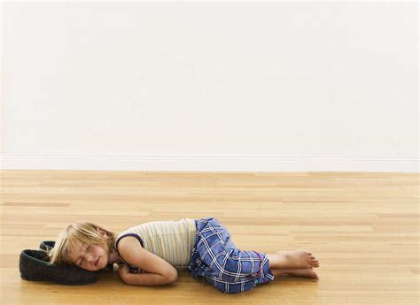 Little boy lying on wooden floor with head on slippers stock photo