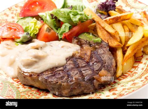 Grilled rib-eye beef steak served with mushroom sauce, salad and potato chips Stock Photo - Alamy