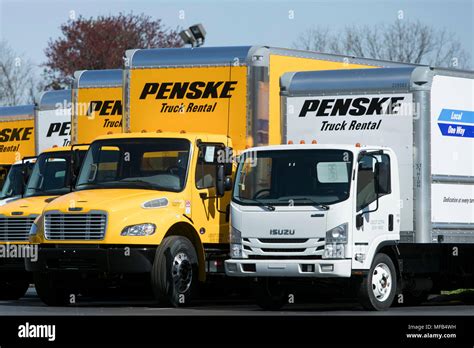 A logo sign and rental trucks outside of a facility occupied by Penske ...