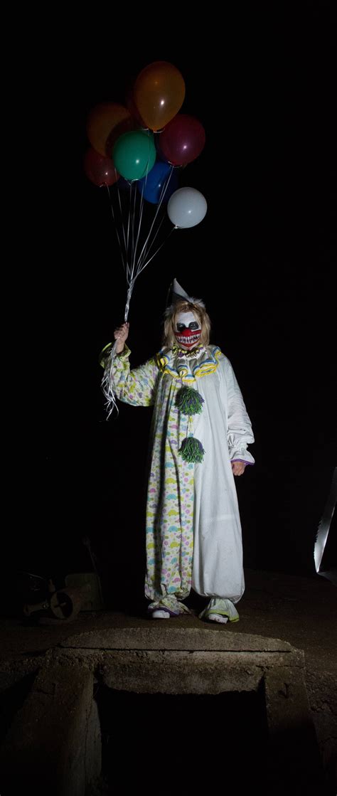 a scary clown holding balloons in the dark