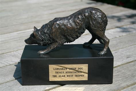 a bronze statue of a dog on a wooden platform with a plaque in front of it