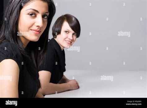 two young businesswomen sitting at conference table Stock Photo - Alamy