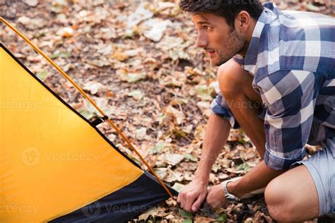 Handsome man setting up a tent 826857 Stock Photo at Vecteezy