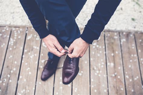 a man in a navy blue suit tying his brown leather shoes, elegant man tying shoes 4k HD Wallpaper