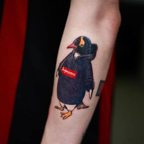 Penguin sporting a Supreme sweater tattoo on the left