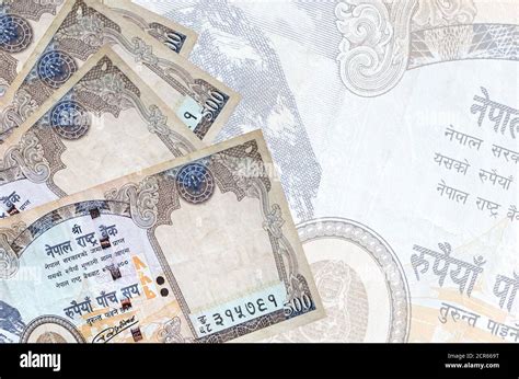 500 Nepalese rupees bills lies in stack on background of big semi-transparent banknote. Abstract ...