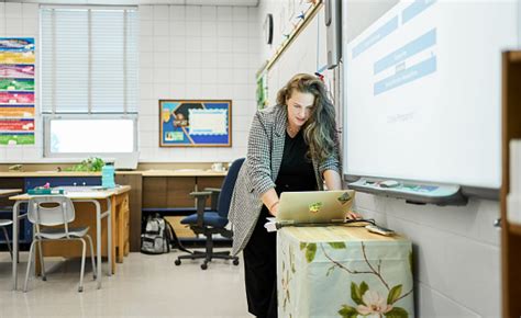 School Teacher Using A Laptop And A Projector For A Classroom Lesson ...