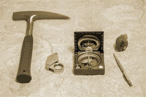 The Geologist`s Hammer And Mineral Are Laid Out On A Wooden Table Against A Topographic Map ...