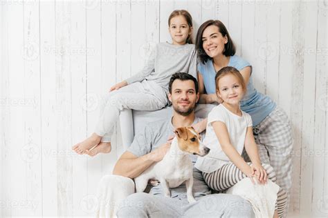 Family portrait. Happy parents with their two daughters and dog pose ...