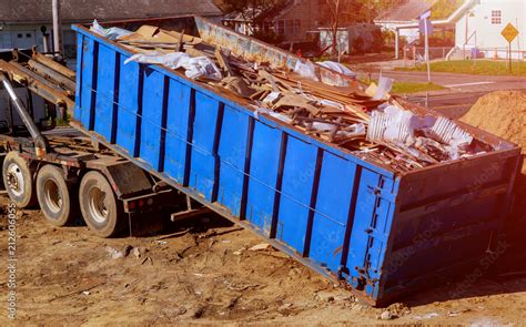 Blue construction debris container filled with rock and concrete rubble ...