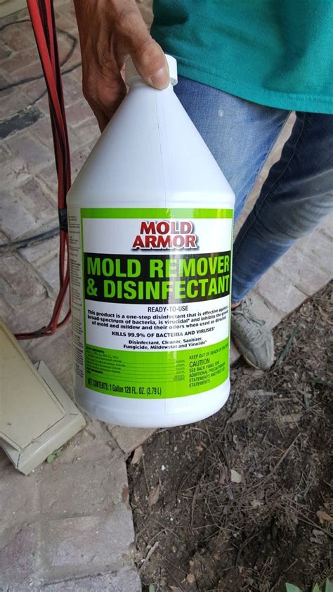 a person holding a bottle of mold remover and disinfectant on the ground