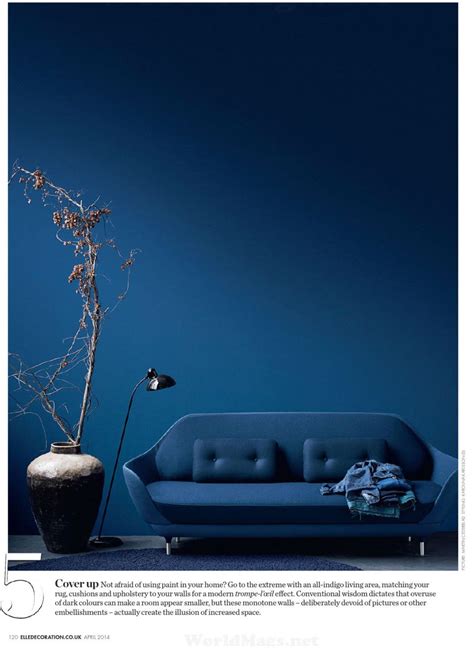 a blue couch sitting next to a vase with a plant in it on top of a table