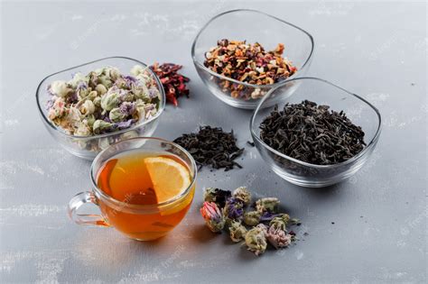 Free Photo | Assorted dried herbs with cup of tea in glass bowls on plaster surface