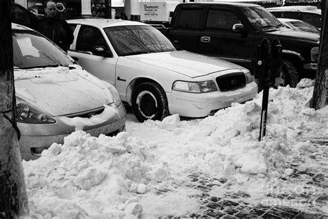 piles of snow cleared from sidewalk piled up at edge of sidewalk in front of parked cars ...