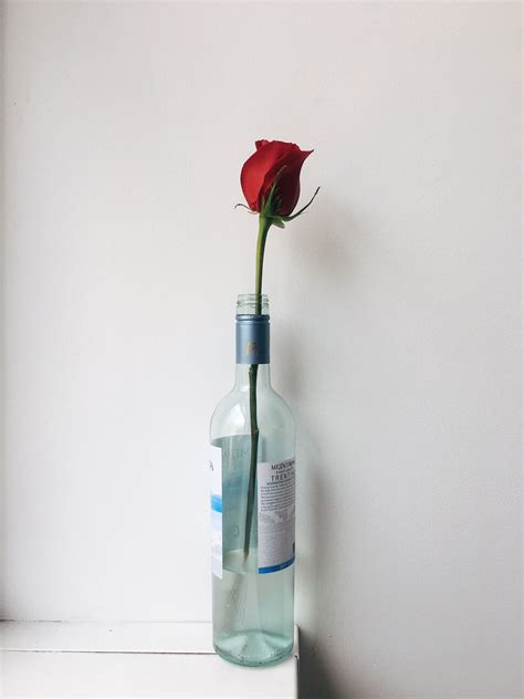 A Flower Arrangement With Roses and Wine Bottles