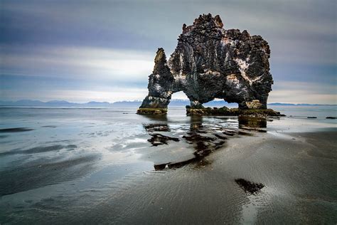 a rock formation in the water on a beach