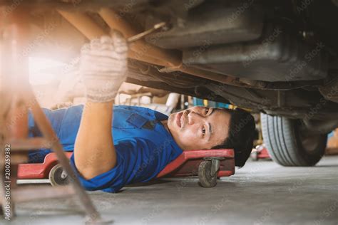 Auto mechanic working under a car, .mechanic lying and repairing under ...