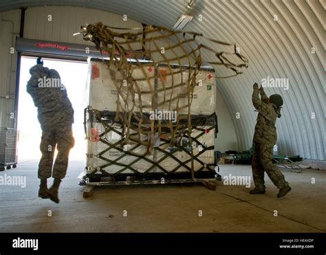 U.S. Air Force airmen toss a pallet net over cargo so they can secure ...