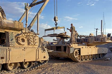 U.S. Marines use an M88A2 Hercules Armored recovery vehicle to reinstall the engine into an M1A1 ...