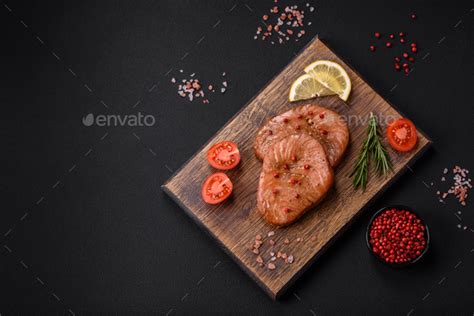 Two baked slices of tuna fillet with spices and herbs Stock Photo by chernikovatv