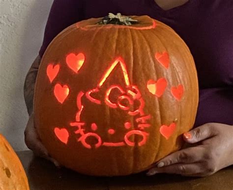 a woman holding a carved pumpkin with hearts on it