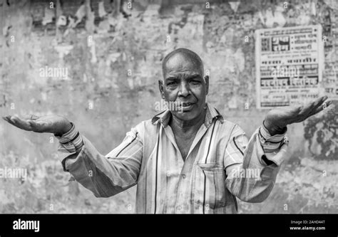 Portrait of man living on streets makes questioning gesture against defaced wall in Udaipur ...